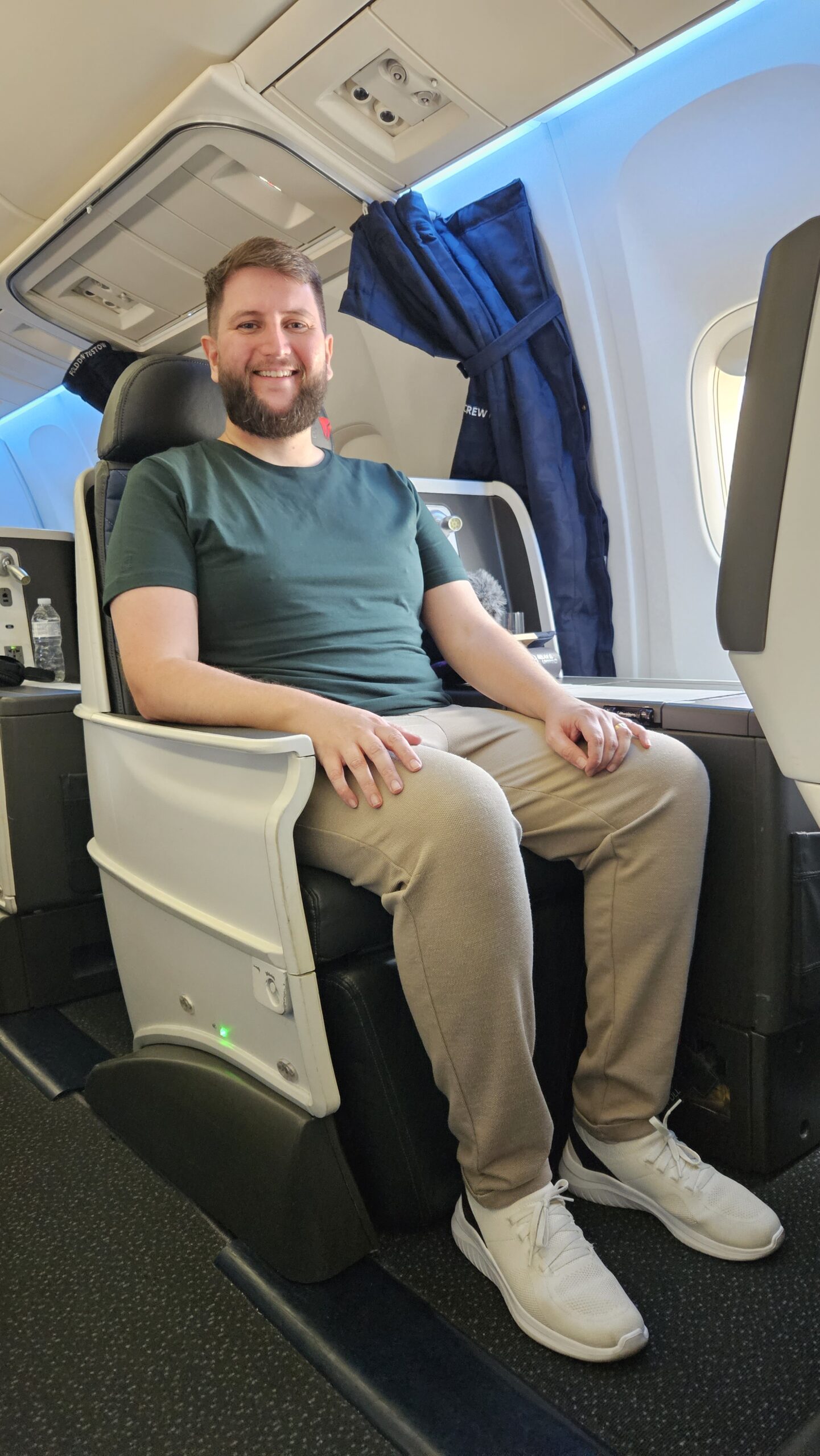 Rudi sentado na poltrona da classe executiva da Delta ao lado da janela do avião