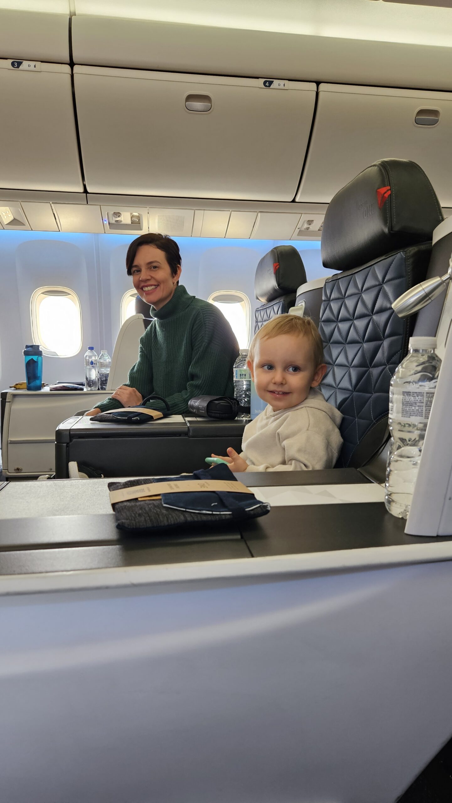 Samuel sorrindo no colo da mãe na cabine executiva da Delta rumo a Nova York