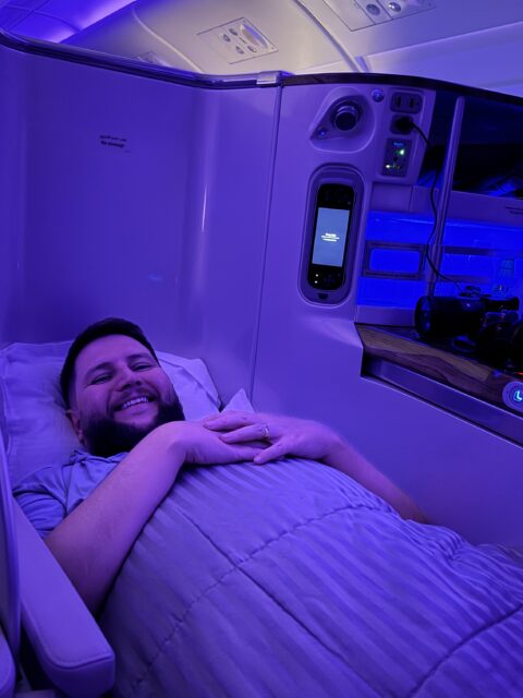 Rudi deitado na cama da executiva Emirates A380 com iluminação azul