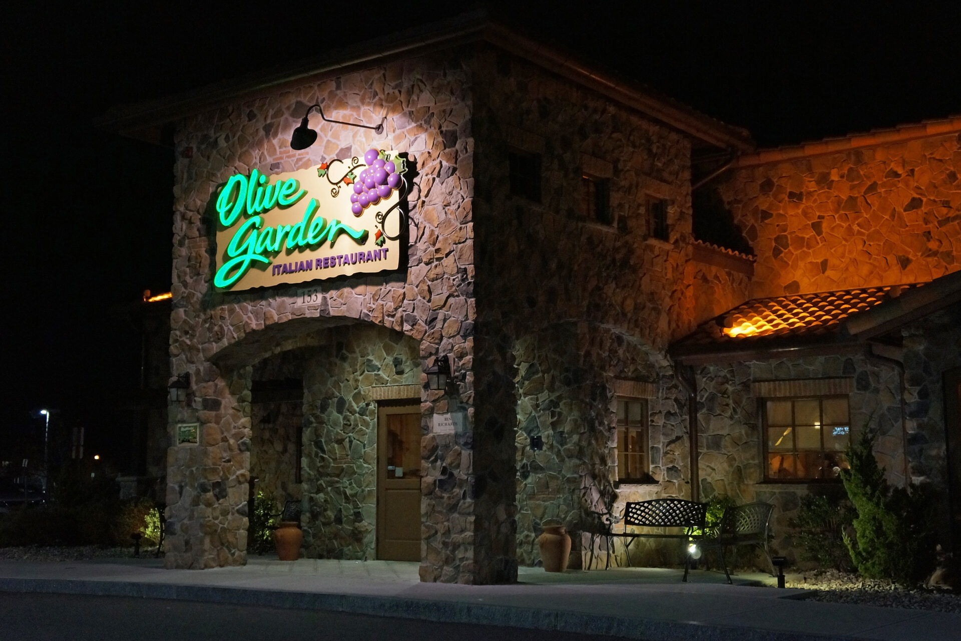 Fachada iluminada de um restaurante Olive Garden à noite