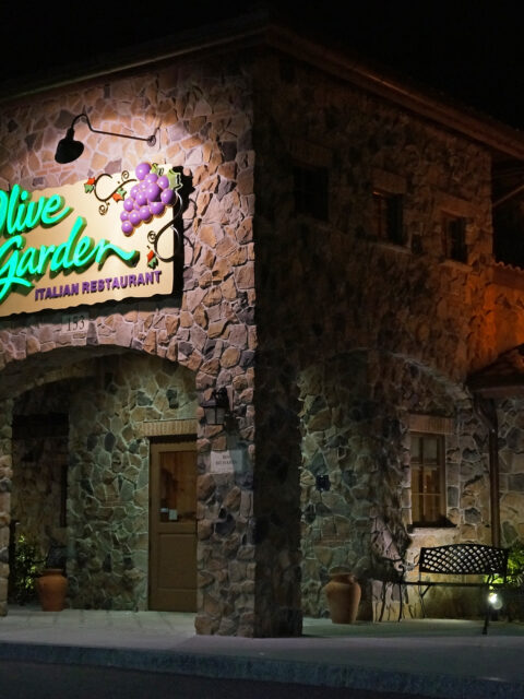 Fachada iluminada de um restaurante Olive Garden à noite