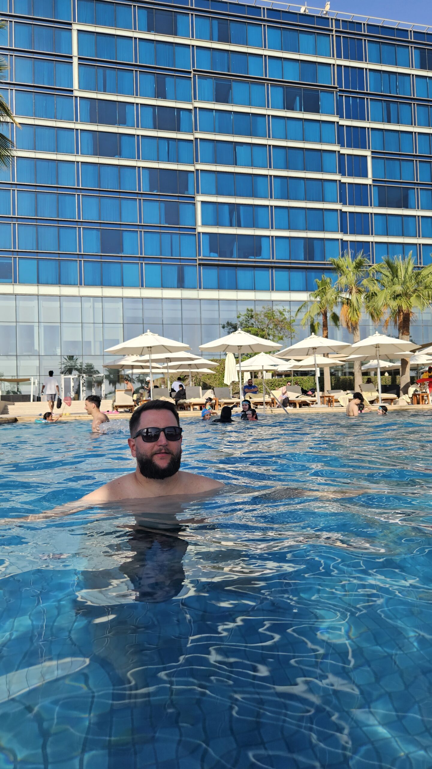 Rudi na piscina do Fairmont Bab Al Bahr com o prédio do hotel ao fundo