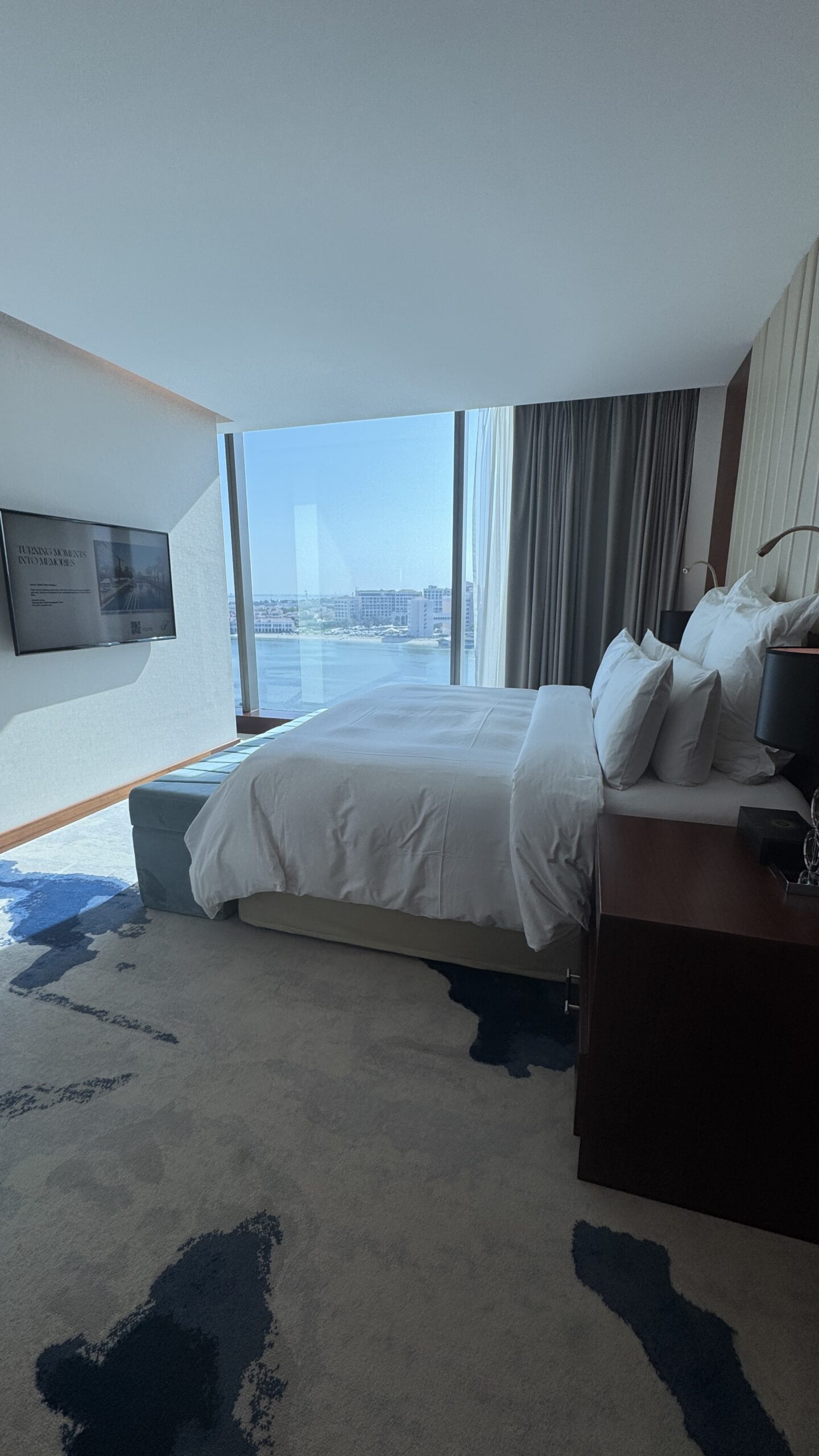 Quarto da suíte do Fairmont Bab Al Bahr com TV LG e vista da cidade pela janela