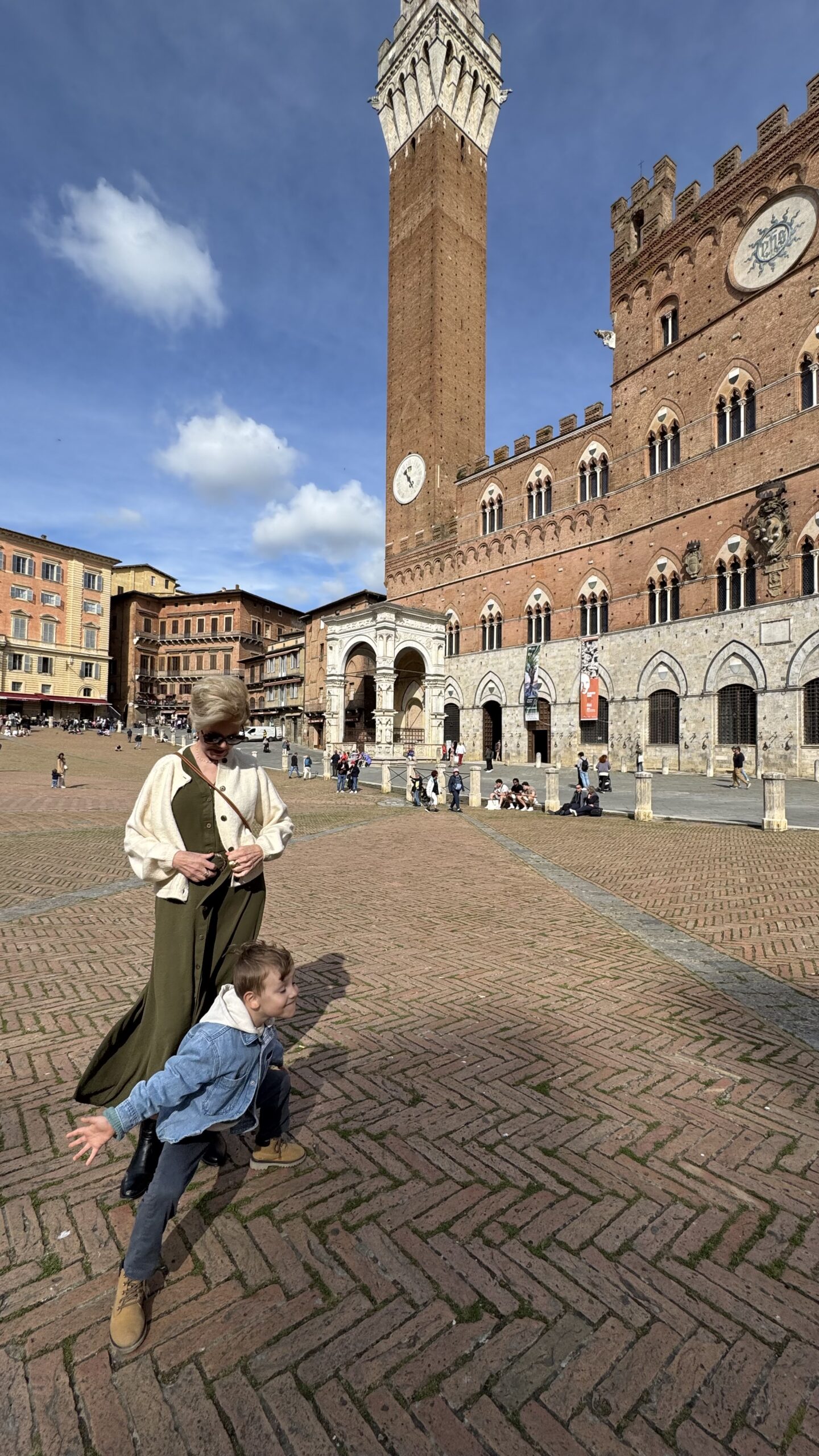 Família na Piazza del Campo em Siena, com a Torre del Mangia ao fundo