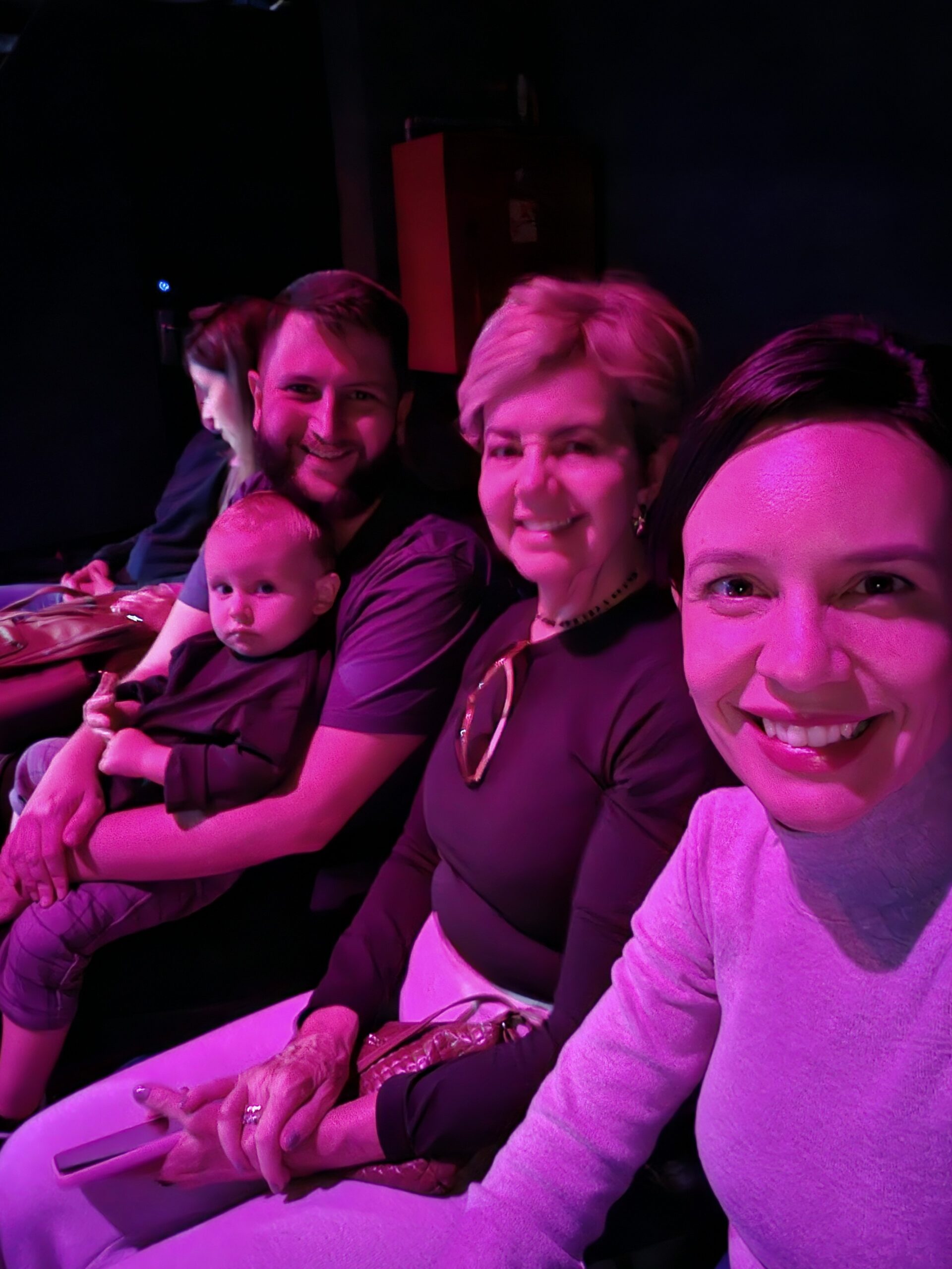 Familia sentada na plateia com iluminacao roxa esperando o inicio de um show na Disneyland Paris