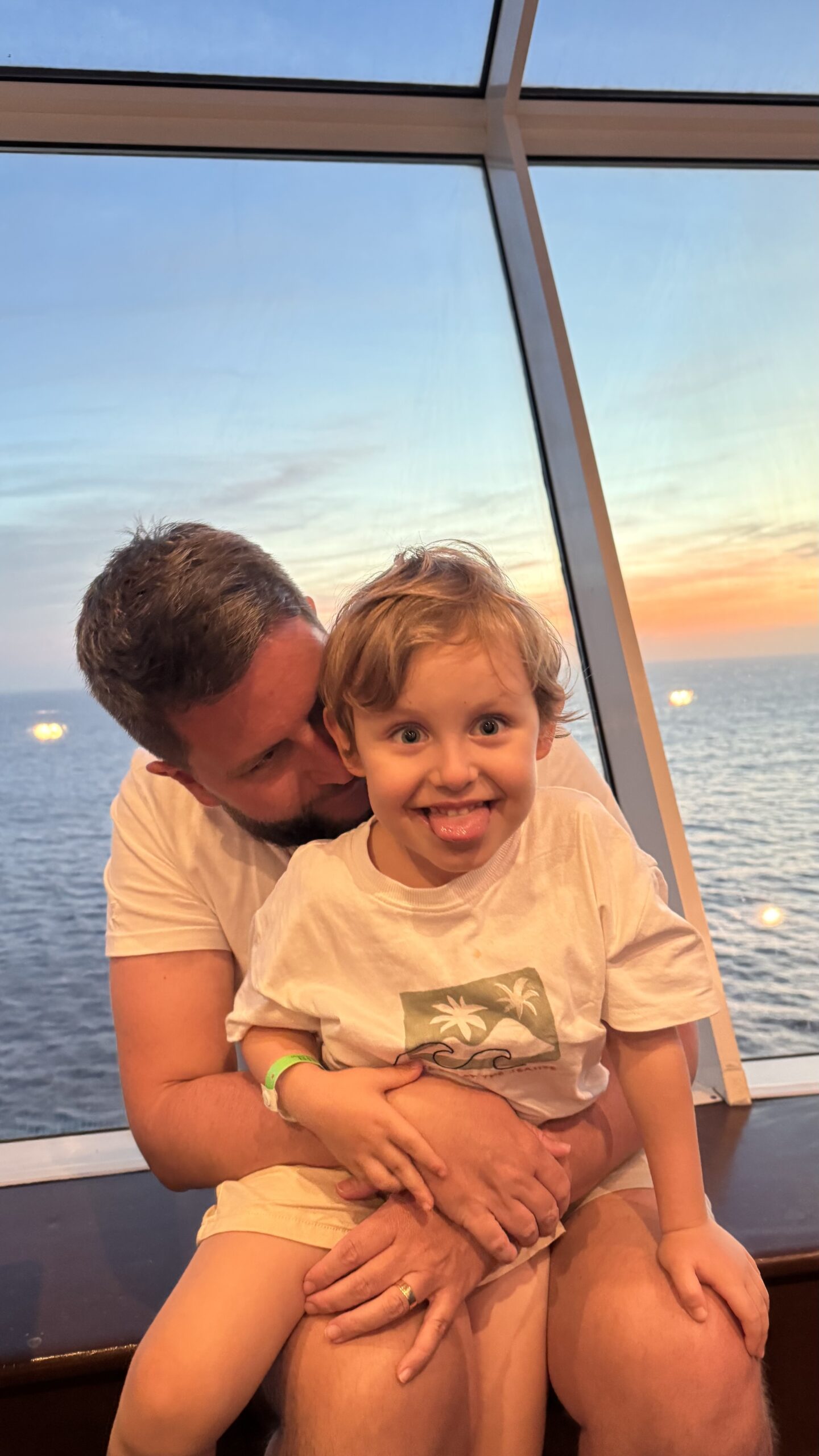 Pai e filho no deck do navio durante o pôr do sol no mar