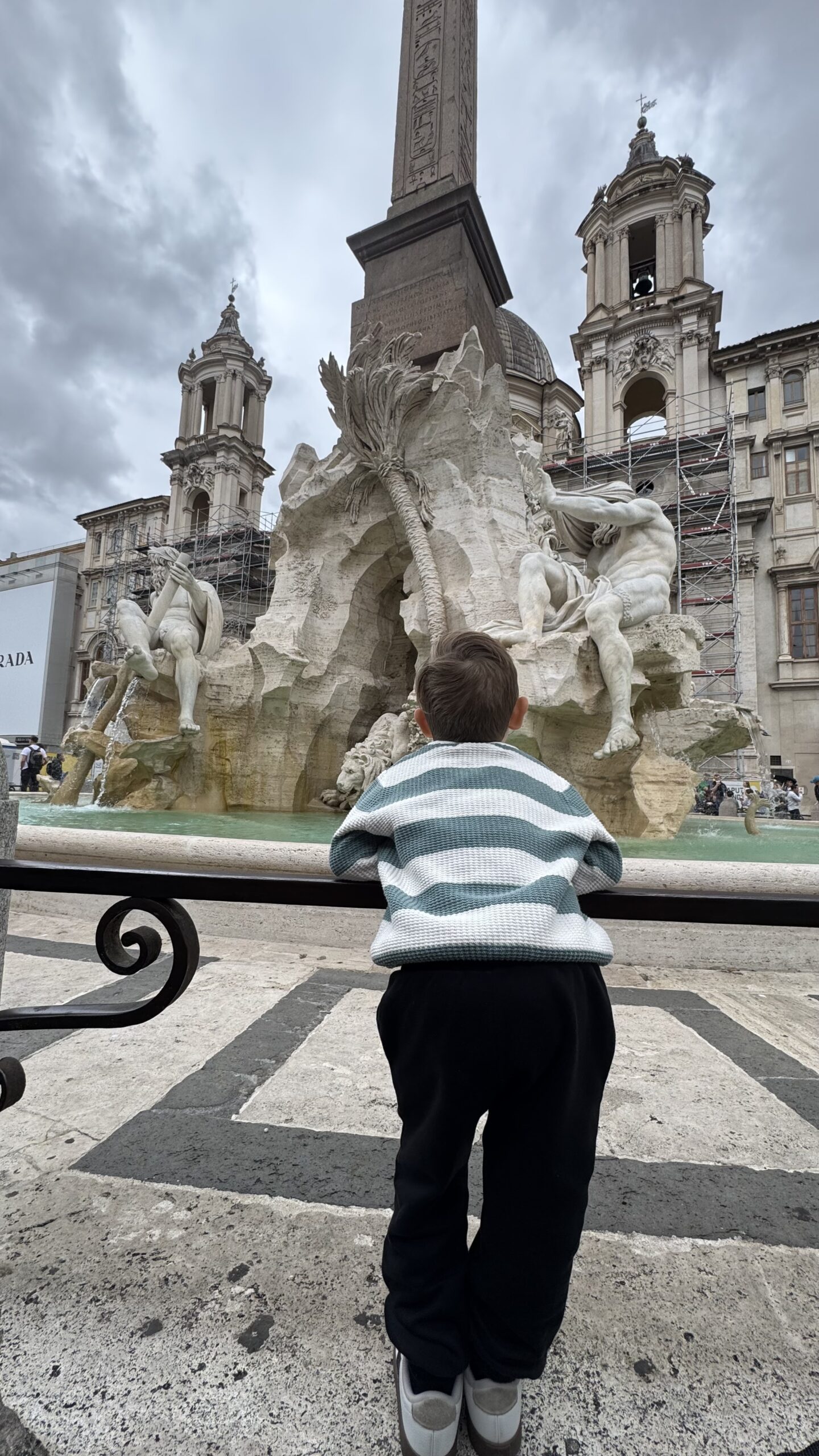 Família em frente à Fontana di Trevi, com as esculturas e a água esverdeada da bacia ao fundo.