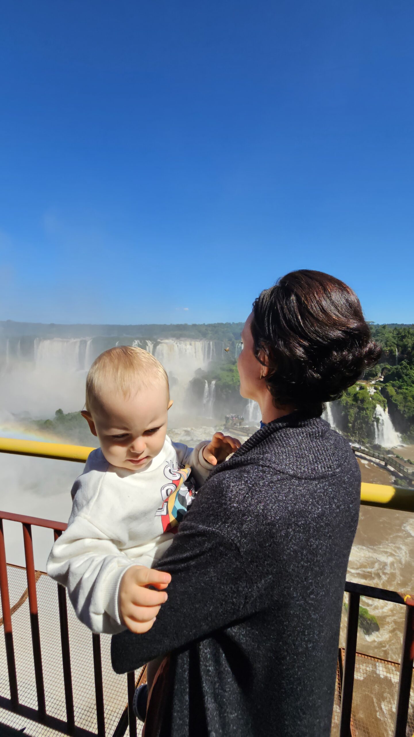 Mãe e Samuel no mirante da Garganta do Diabo com arco-íris nas Cataratas do Iguaçu