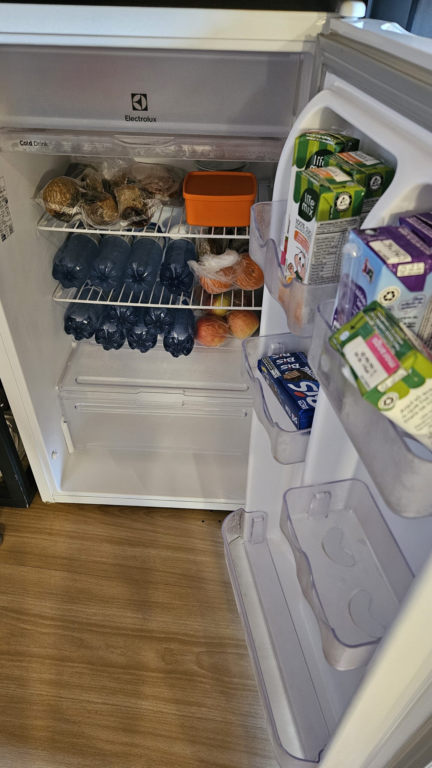 Frigobar aberto no quarto da Pousada Luar da Ilha, com bebidas e frutas