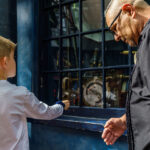 Pai e filho testam varinha interativa em vitrine de loja em Hogsmeade, na Universal Islands of Adventure