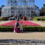 Familia em frente ao canteiro de flores rosa com a estufa de ferro e vidro do Jardim Botanico de Curitiba ao fundo