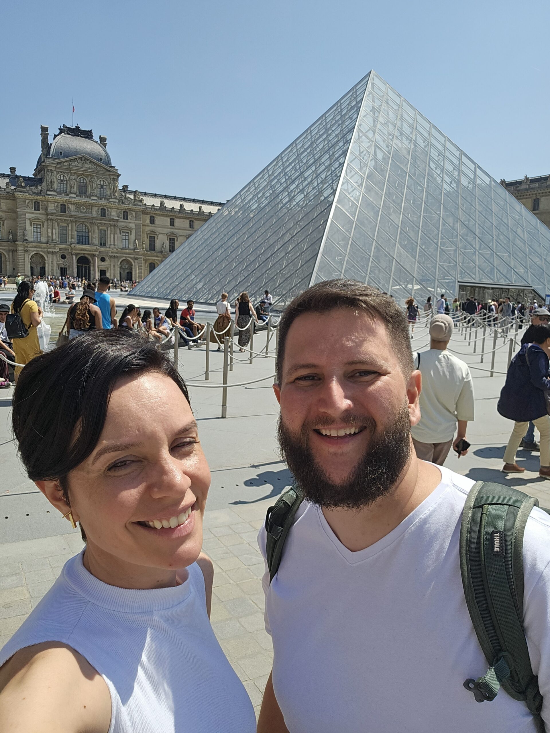 Casal em frente à pirâmide do Louvre