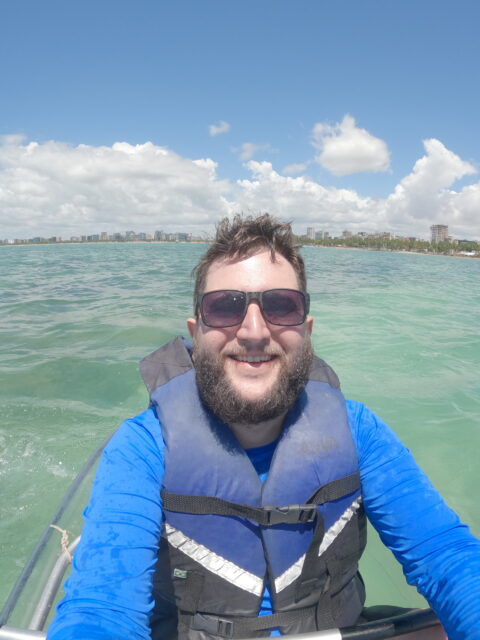 Rudi de caiaque na orla de Maceió com o skyline ao fundo