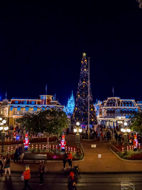 Main Street USA decorada para o Natal à noite no Magic Kingdom, com árvore de Natal iluminada e o castelo ao fundo