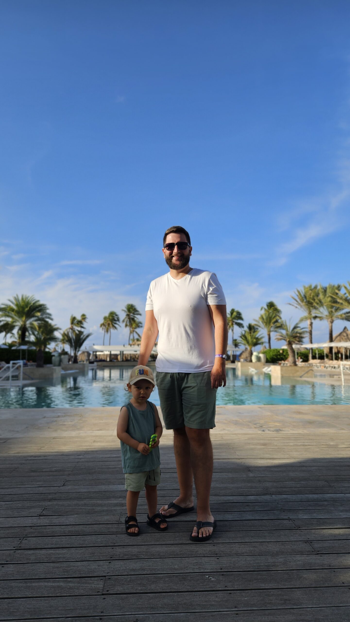 Rudi e Samuel caminhando no deck de madeira do Mangrove Beach Resort com a piscina ao fundo