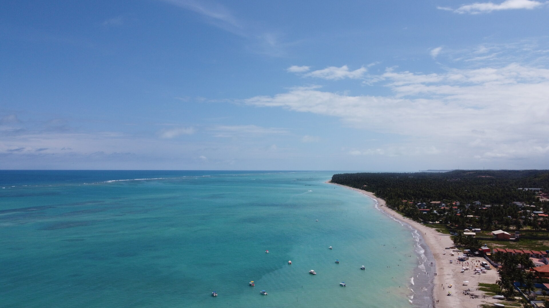 Vista aerea da orla de Maragogi com agua azul turquesa e recifes visiveis na maré baixa