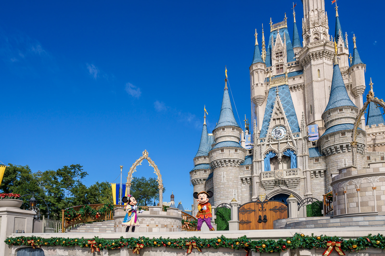 Mickey e Minnie fantasiados em frente ao Castelo da Cinderela decorado para o Natal no Magic Kingdom