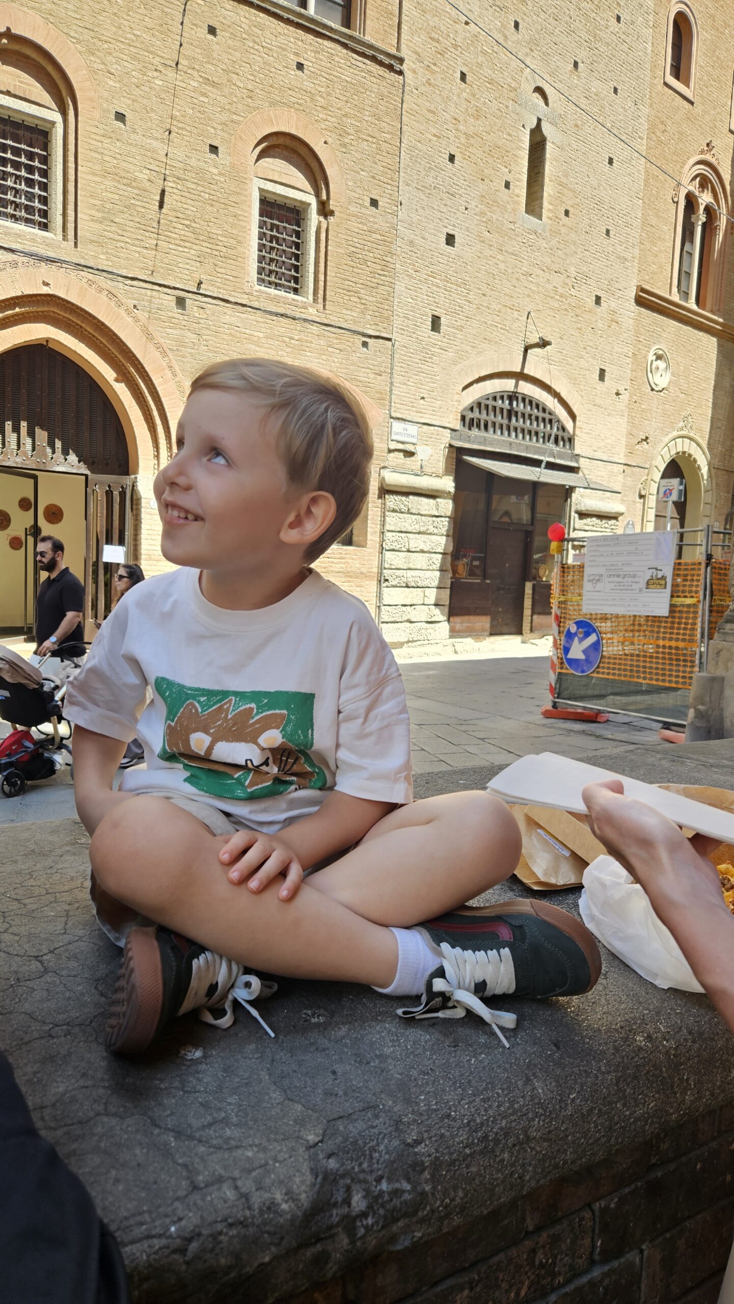 Samuel sentado na rua comendo o tagliatelle para viagem da Sfoglia Rina em Bolonha