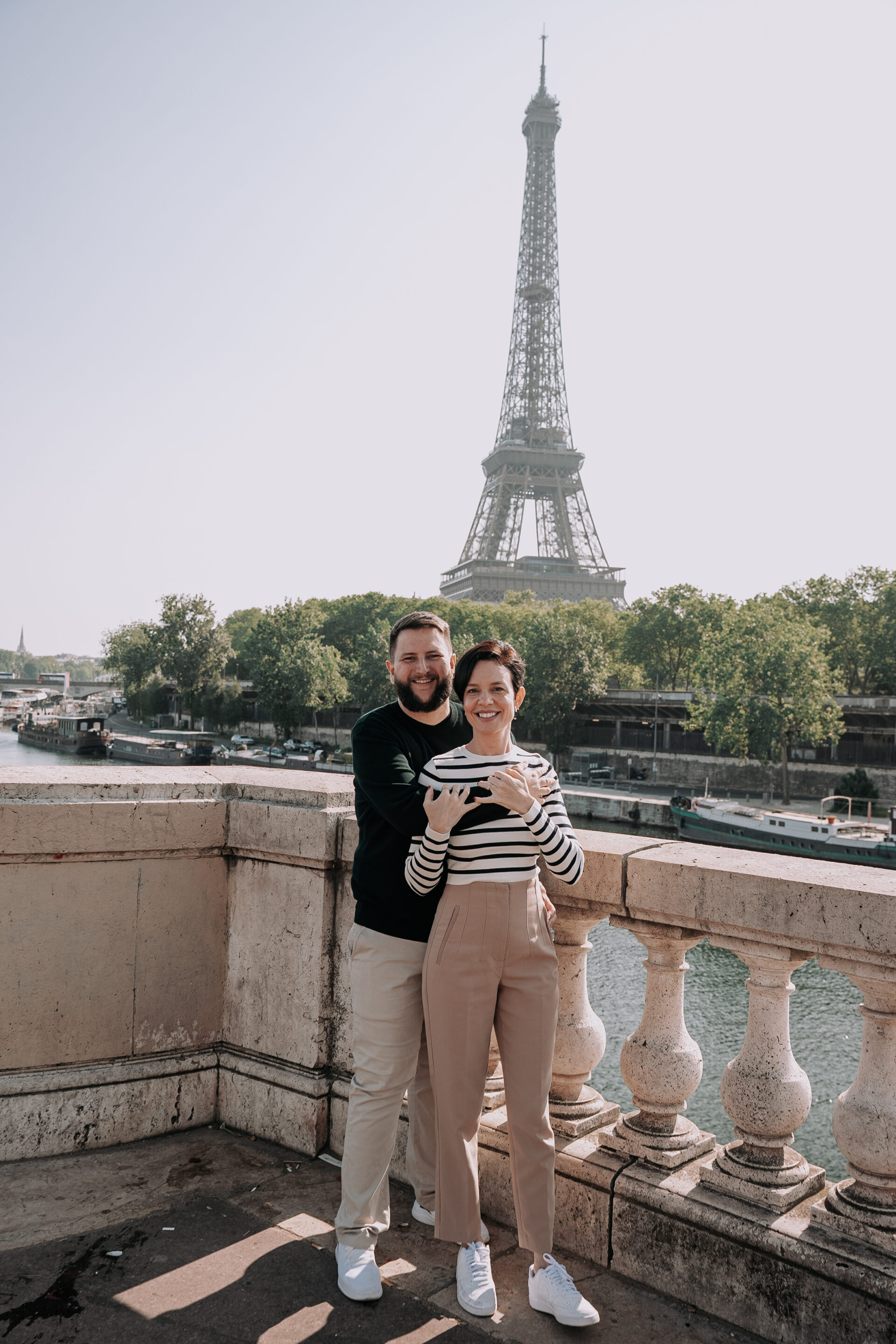Casal com o bebê no colo posando em frente a bicicletas com a Torre Eiffel ao fundo, em ensaio fotografico profissional em Paris