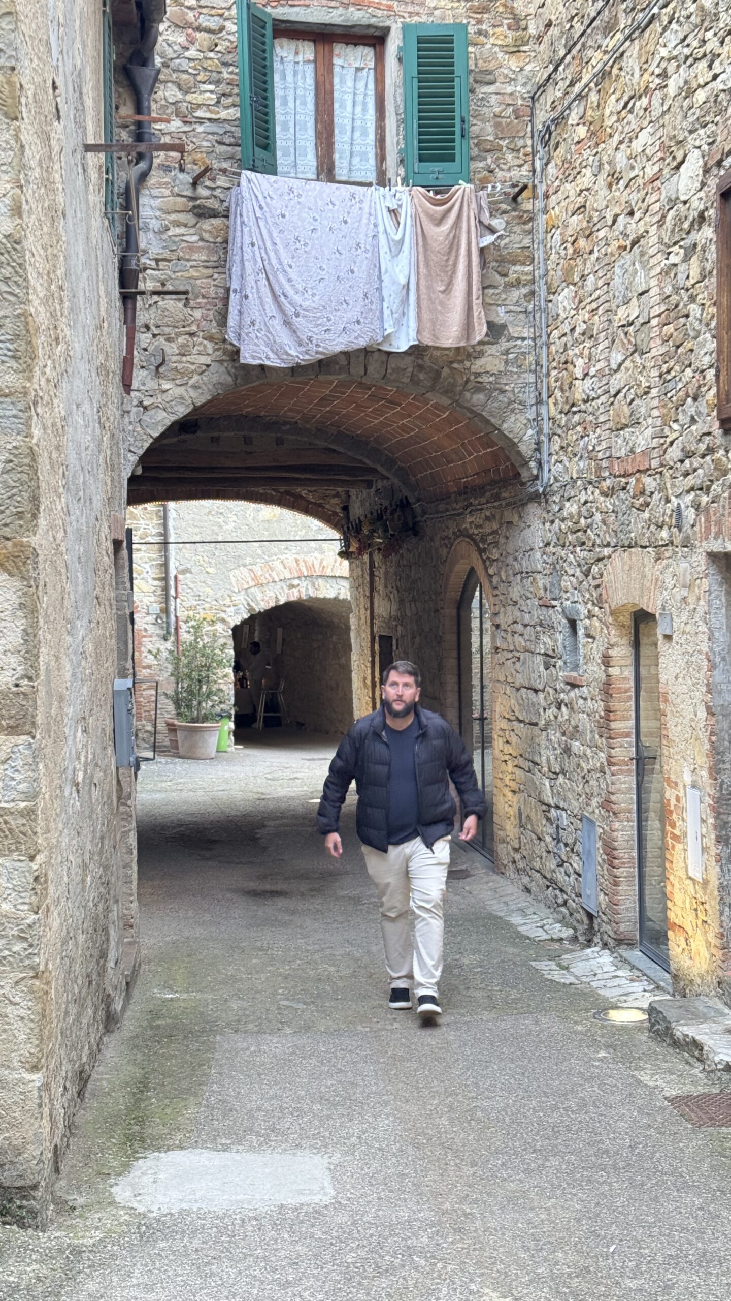 Homem caminhando por passagem medieval coberta em Castellina in Chianti