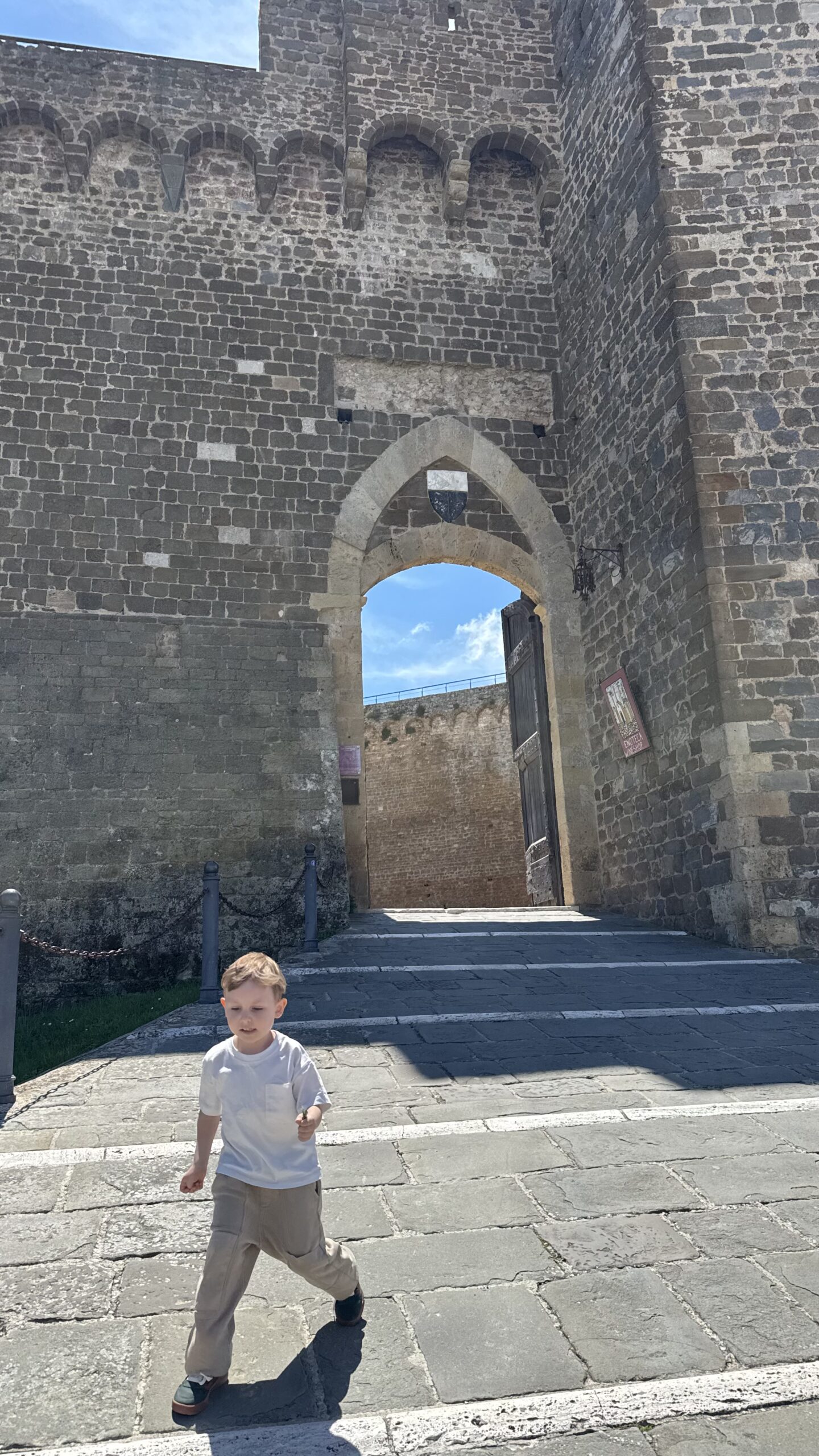 Criança correndo em direção ao portão de entrada da Fortezza de Montalcino