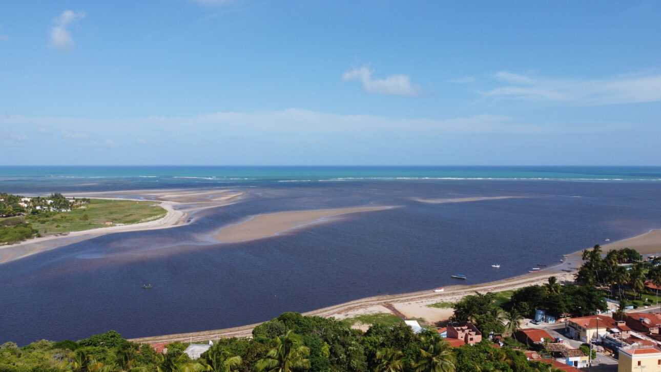 Vista aerea da foz do Rio Manguaba encontrando o mar em Porto de Pedras, Alagoas, com faixas de areia expostas na mare baixa