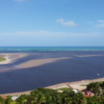 Vista aerea da foz do Rio Manguaba encontrando o mar em Porto de Pedras, Alagoas, com faixas de areia expostas na mare baixa
