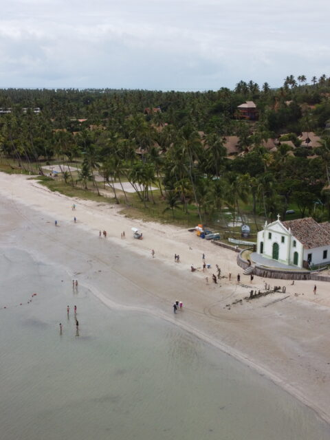 Vista aérea de drone da Praia dos Carneiros com a igrejinha branca e verde na areia