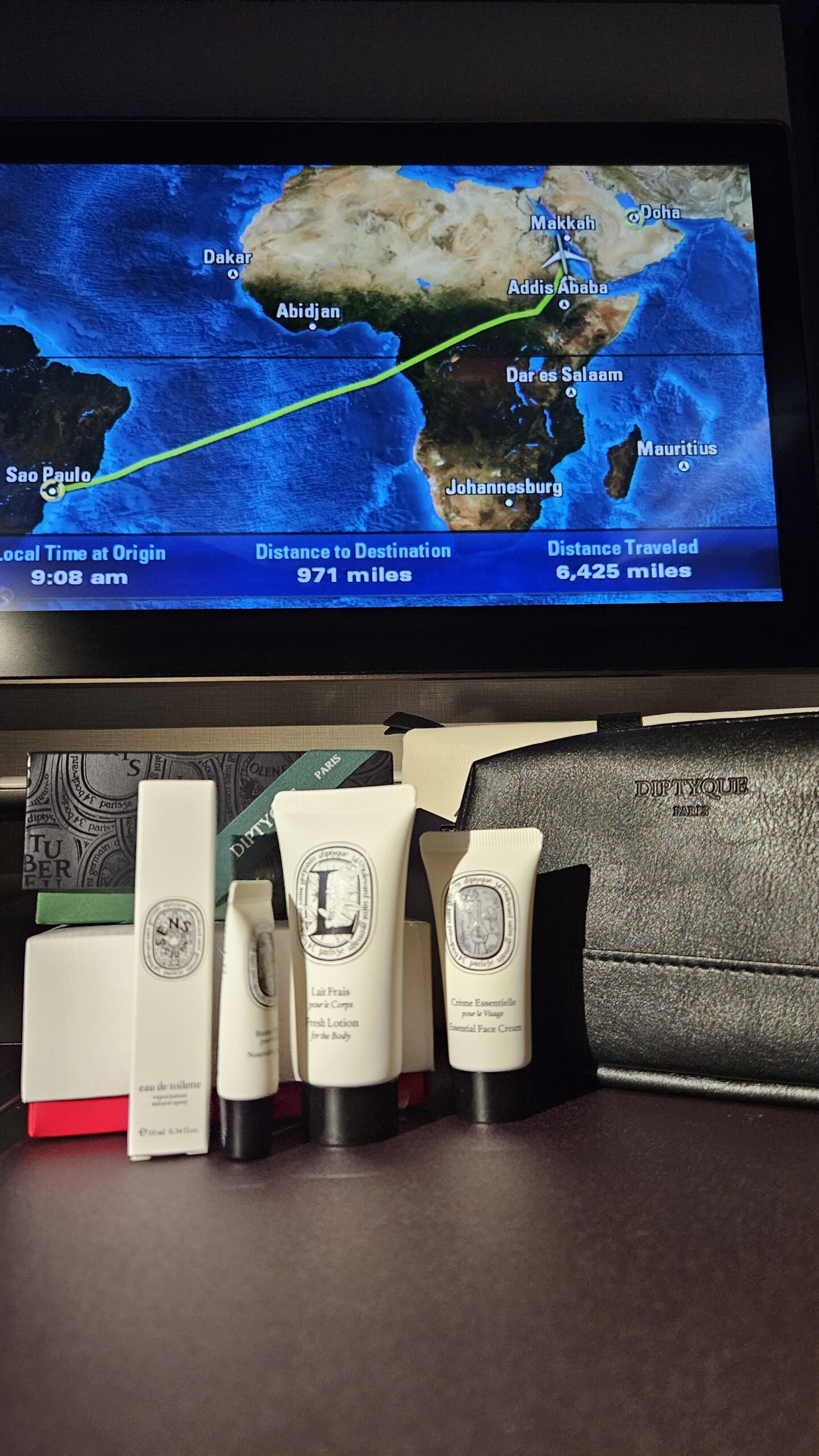 Amenity kit Diptyque da Qatar Airways ao lado da tela com o mapa de voo Buenos Aires a Doha