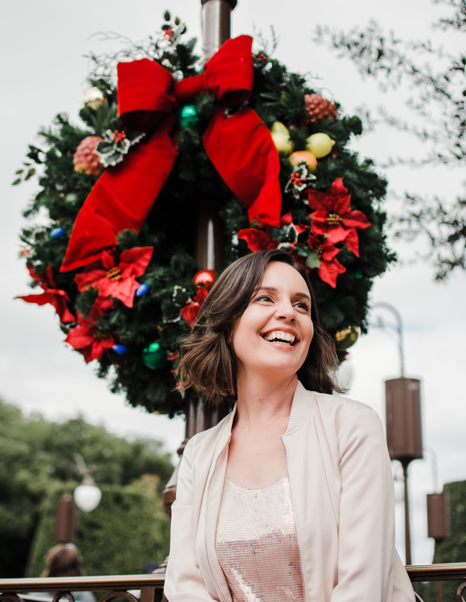 Retrato da Carol sorrindo em frente a guirlanda de Natal decorada na Main Street do Magic Kingdom