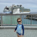 Dois navios da Royal Caribbean atracados lado a lado em CocoCay, com criança em primeiro plano
