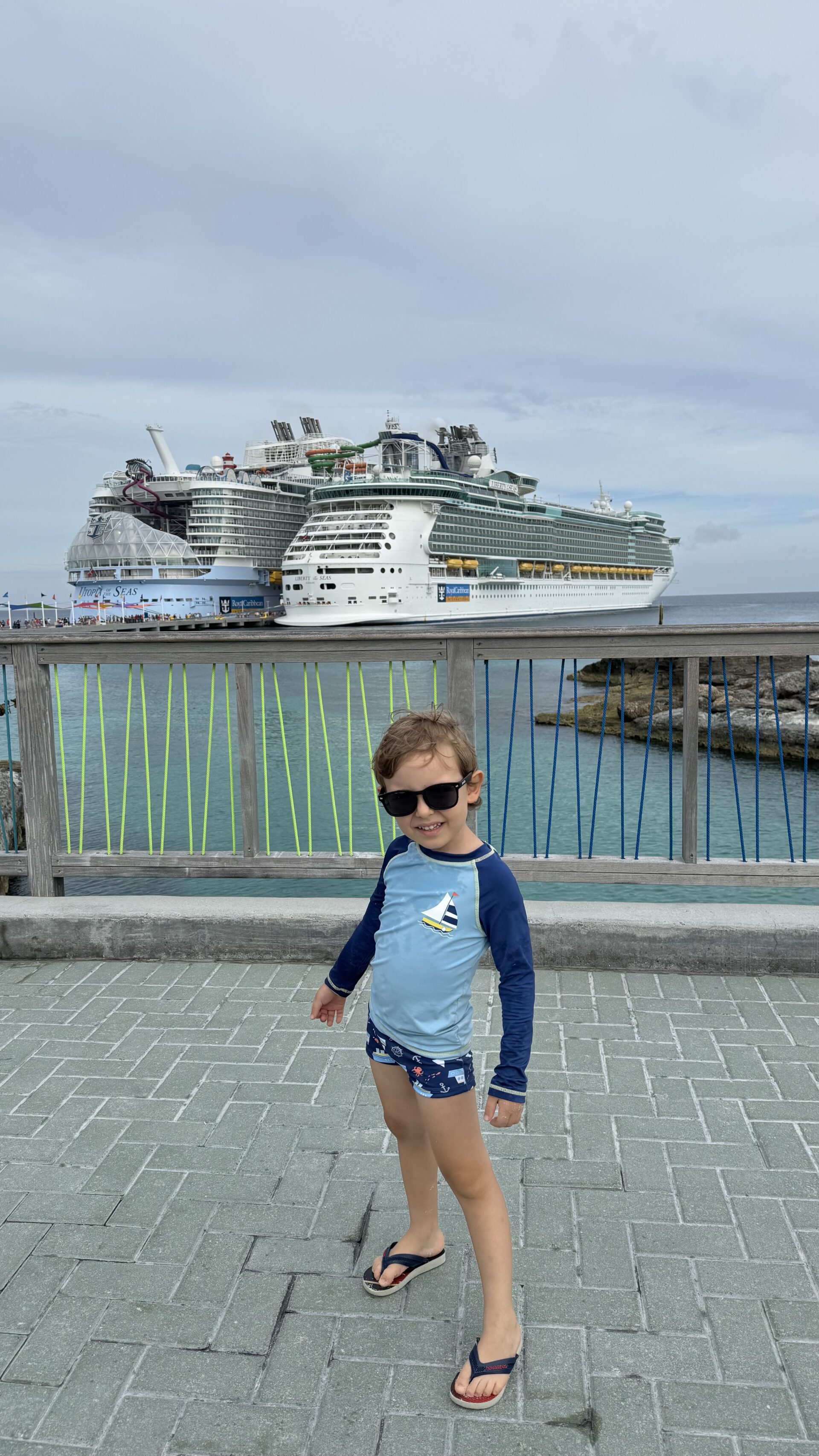 Dois navios da Royal Caribbean atracados lado a lado em CocoCay, com criança em primeiro plano
