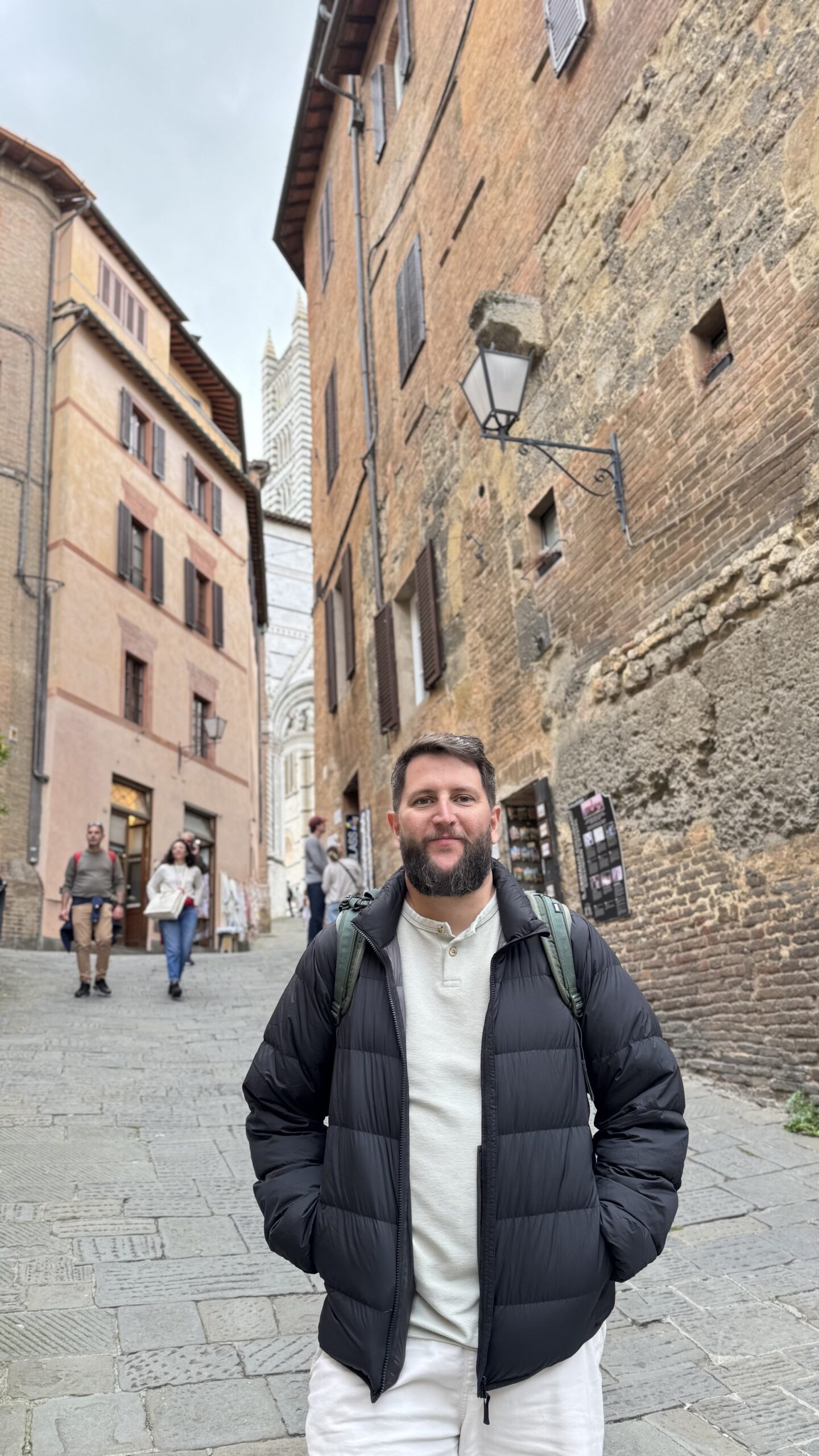 Rua estreita de Siena com o campanile listrado do Duomo ao fundo