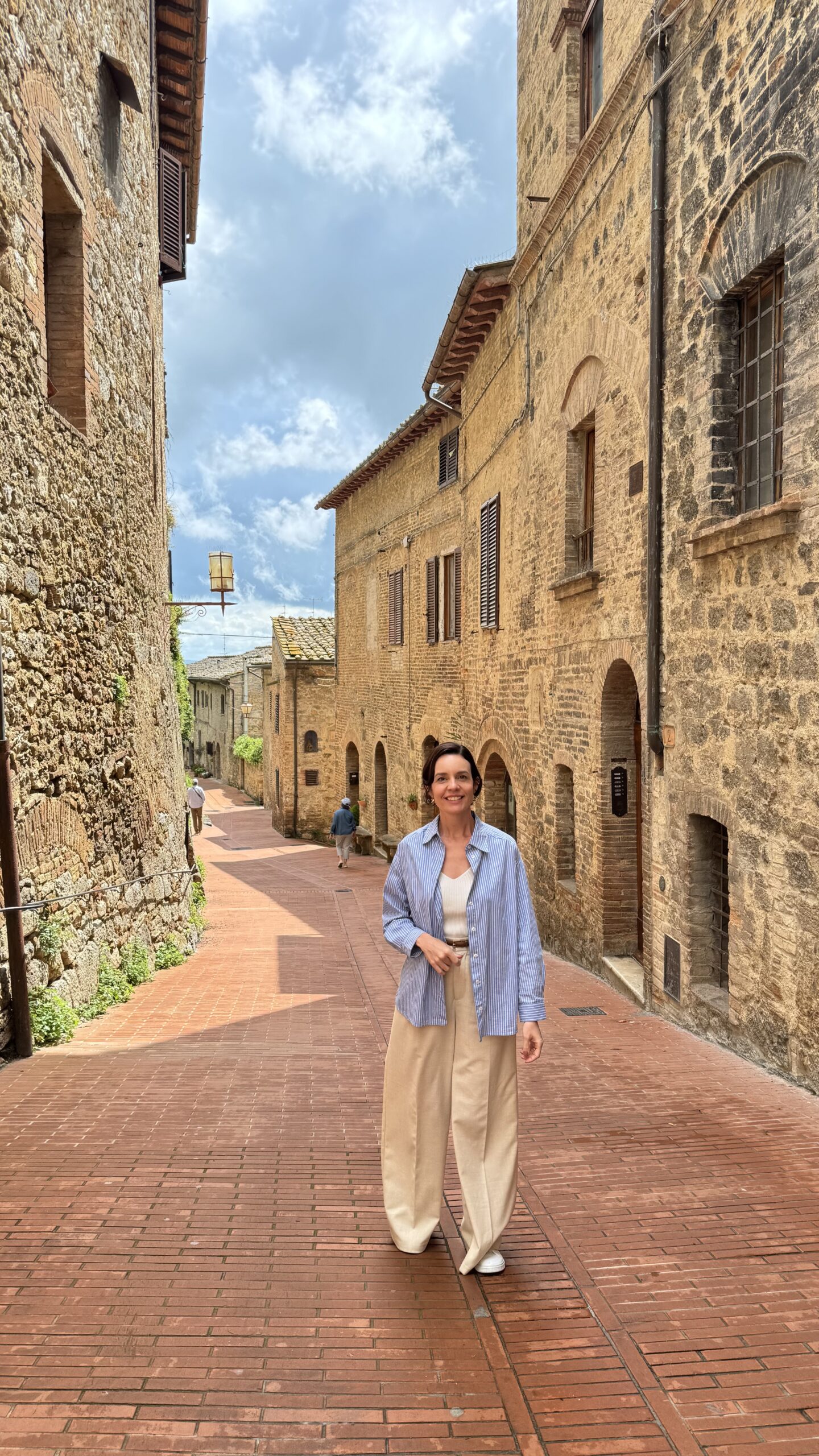 Mulher caminhando por uma ruela estreita de pedra no centro histórico de San Gimignano