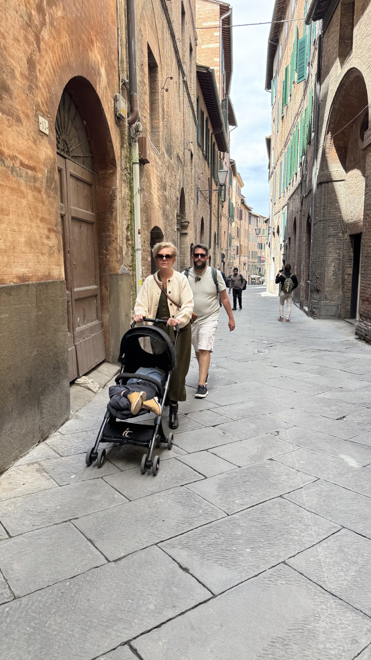 Família caminhando por uma rua medieval estreita no centro histórico de Siena