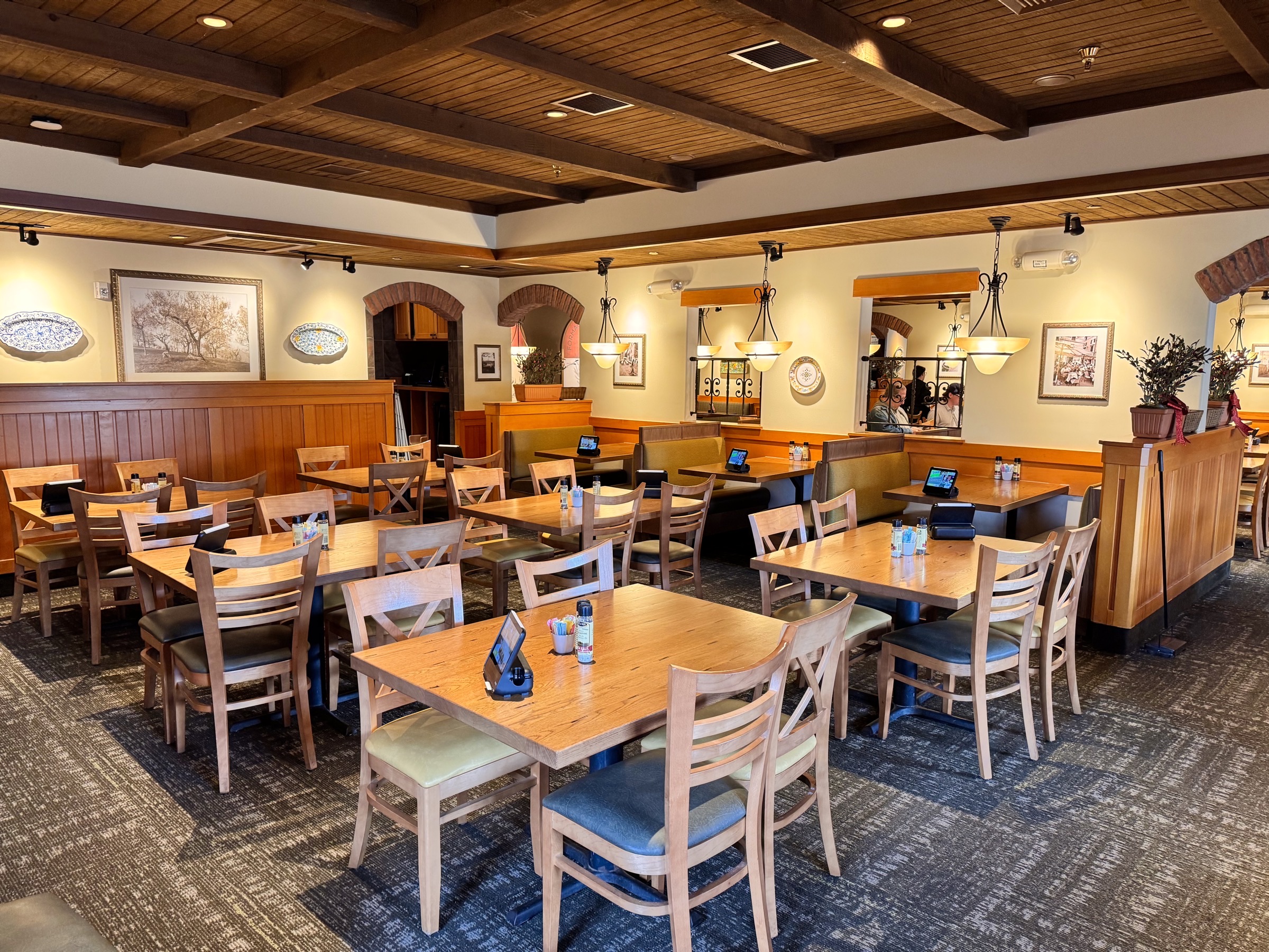 Salão interno de um restaurante Olive Garden com mesas dispostas