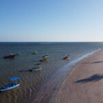 Vista aérea da praia de São Miguel dos Milagres ao entardecer com jangadas na maré baixa