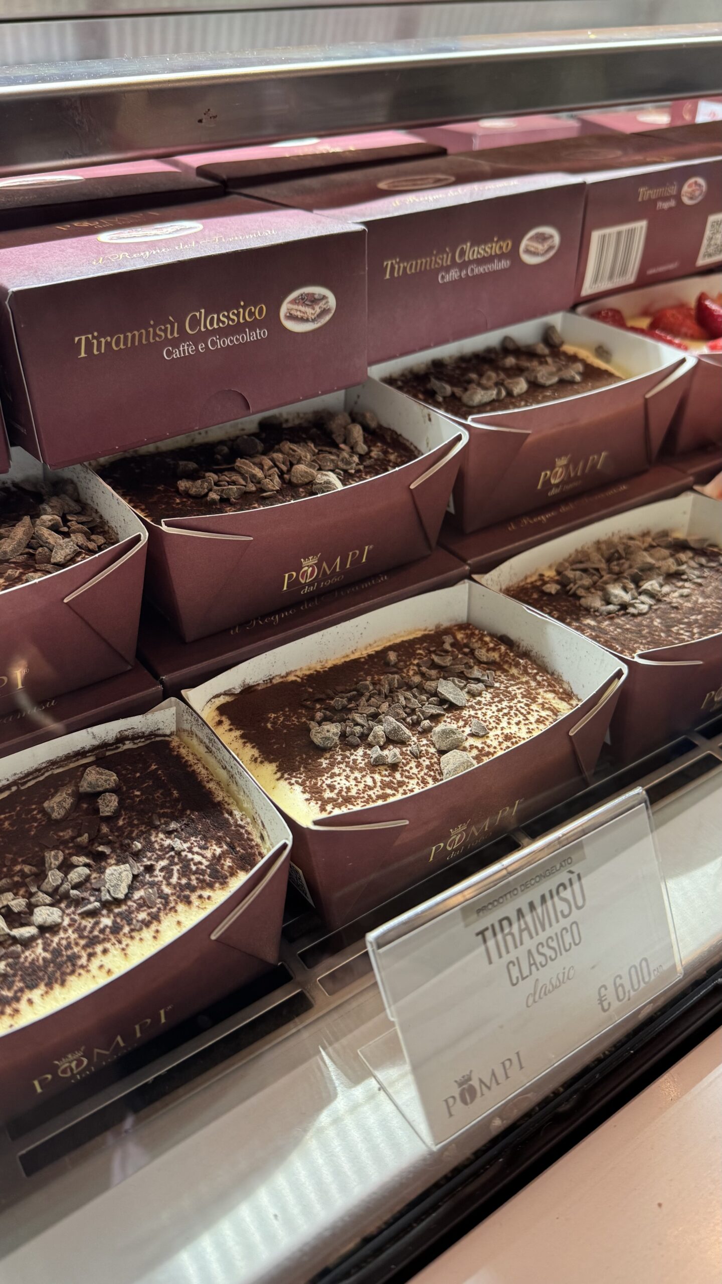 Caixinhas de tiramisù clássico na vitrine da Pompi, com cobertura de cacau e raspas de chocolate.