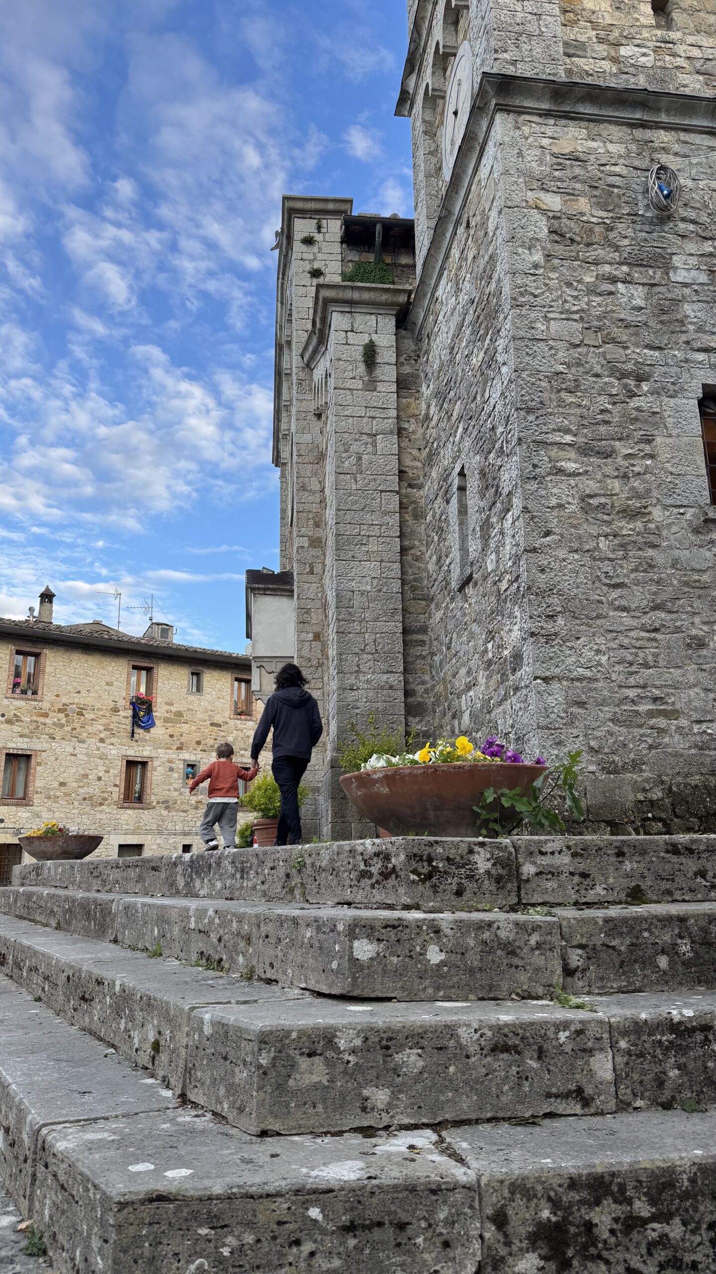 Família subindo escadaria de pedra perto de torre medieval em Castellina in Chianti